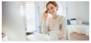 A woman answering a phone call while holding a cup of coffee