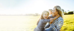A mother, grandmother, and daughter sitting together in a field, enjoying a joyful and peaceful moment outdoors