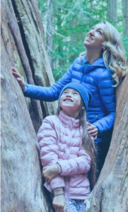 A mother and her daughter standing together in a large tree